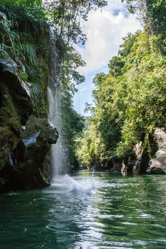 un rio recibe una cascada con hermosos colores y transparencia